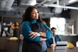 Confident woman in apron standing in café.
